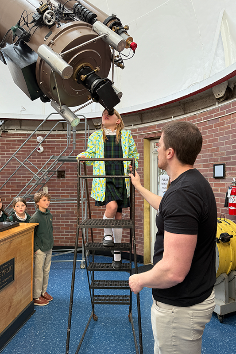 Child looks through telescope at Vanderbilt Dyer Observatory while classmates and guide observe inside the dome.